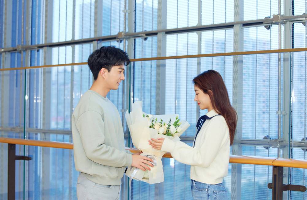 homme offre un bouquet de fleurs &agrave; une jeune femme