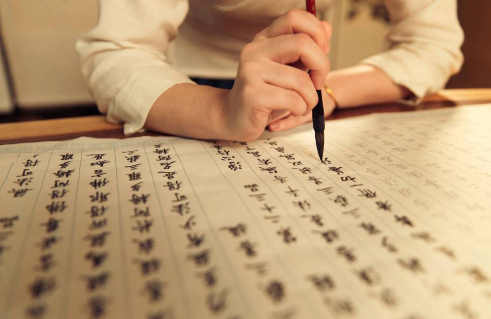 personne qui trace les caract&egrave;res chinois au pinceau