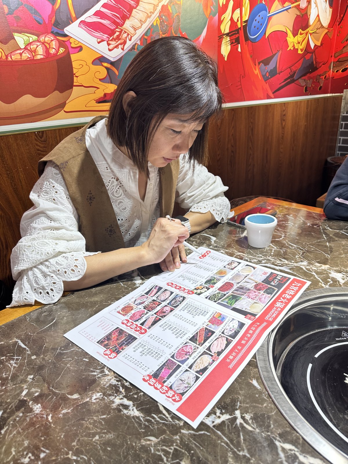 Haixia regarde le menu dans un restaurant de fondue &agrave; Chongqing