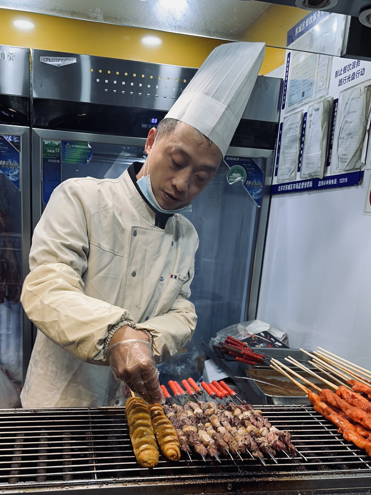 Chef pr&eacute;parant des brochettes grill&eacute;es dans un hutong de P&eacute;kin